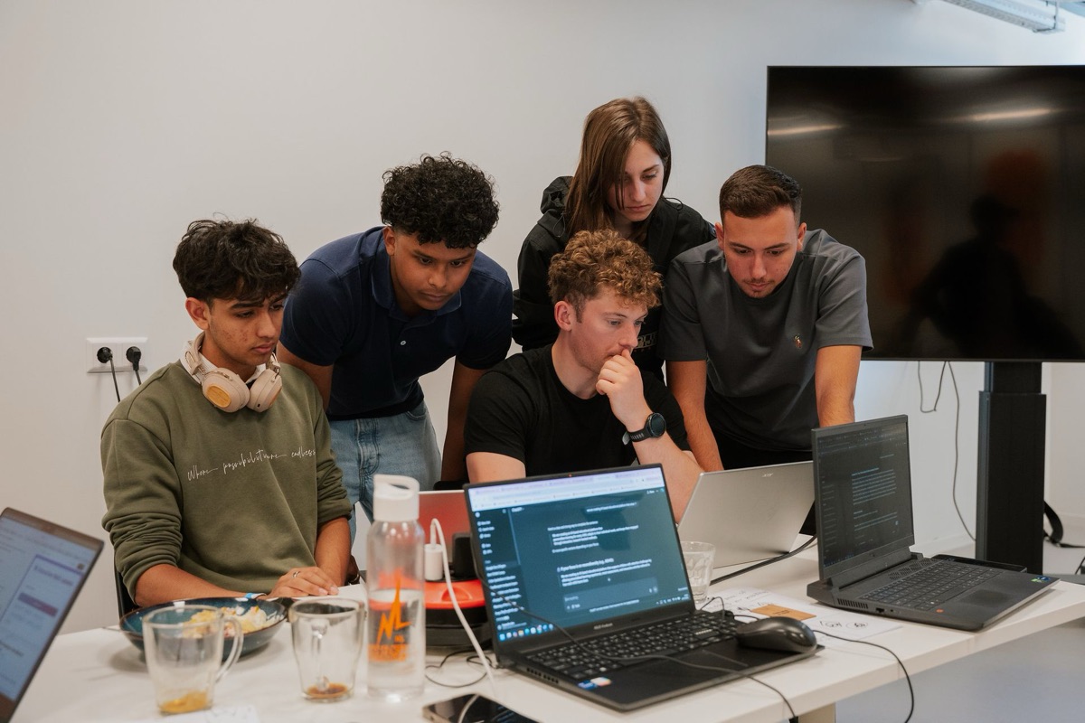 Students gathered around a laptop, building together